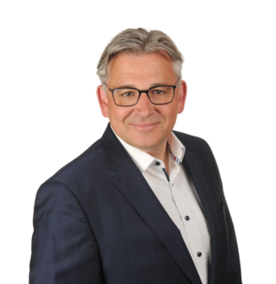 Porträt einer Person im dunklen Anzug vor hellem Hintergrund